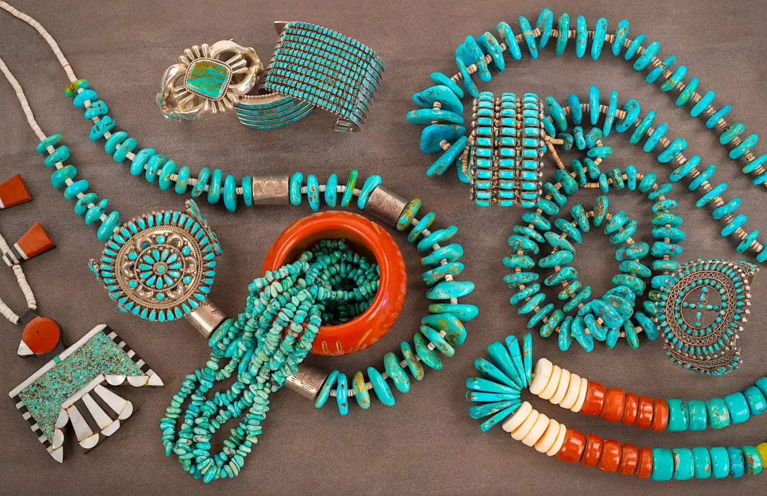 Collection of turquoise and coral Native American jewelry pieces including necklaces, bracelets, and decorative pins.
