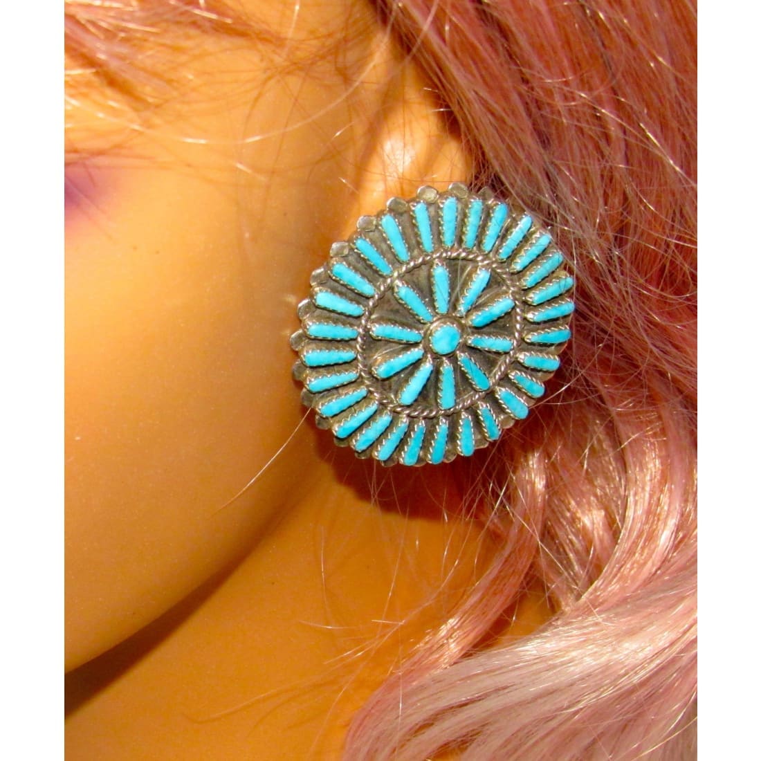Zuni petit point turquoise earrings in a circular design worn on ear with silver detailing